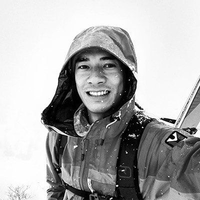 Selfie en blanco y negro de hombre con capucha y esquís a la espalda