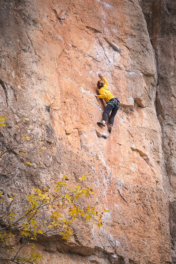 Escaladora vestida de amarillo escalando un muro rojizo de Siurana
