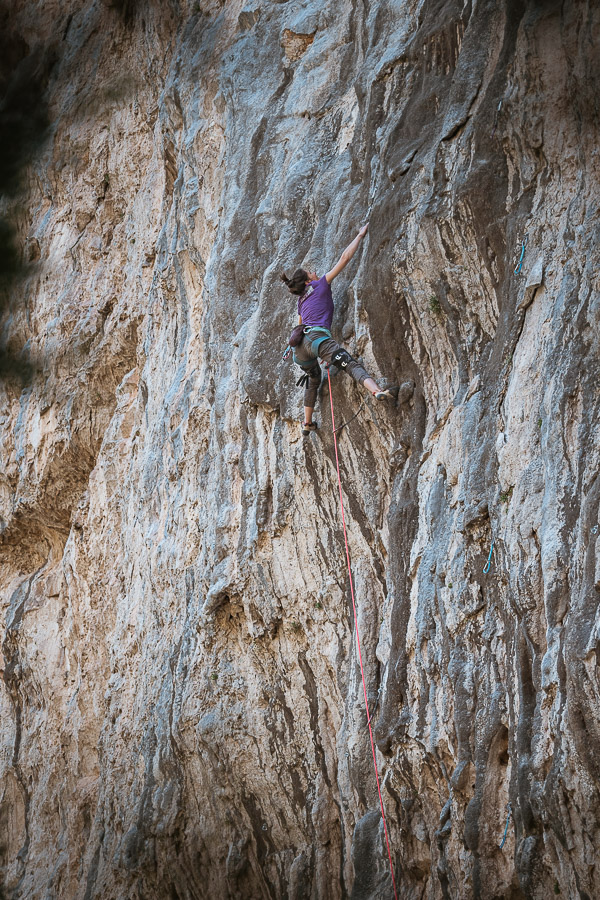 Chica de lila escalando un gran muro de chorreras